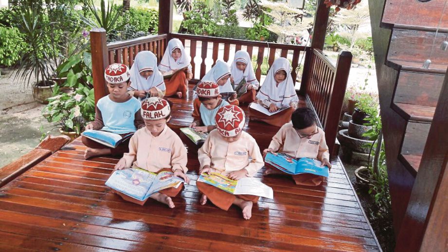 MURID menghabiskan masa membaca buku di pondok yang diubah suai menjadi perpustakaan mini  berkonsepkan ciri binaan rumah Melayu di Kampung Permatang, Kuala Sungai Baru, Masjid Tanah.