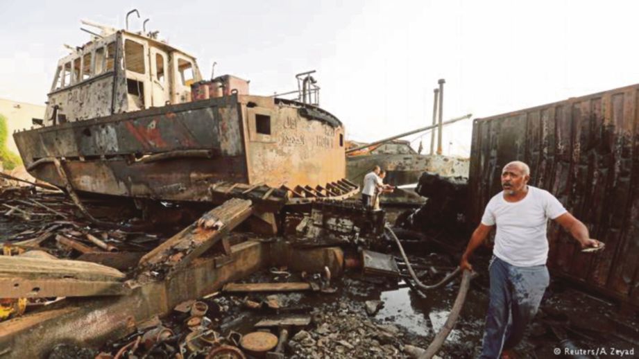 ORANG ramai menggunakan hos untuk memadamkan kebakaran akibat serangan tentera Yaman di pelabuhan Hodeida. - Reuters