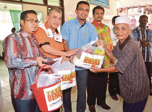  Roslan  (dua kiri) menyampaikan bantuan kepada Tohir pada  Majlis Bantuan Mangsa Banjir Kuala Selangor sumbangan dari Tabung Bencana NSTP Media Prima di SK Parit Mahang. 