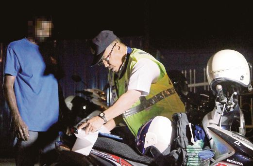 Anggota polis memeriksa   penunggang  motosikal yang melakukan kesalahan dalam operasi khas, kelmarin.