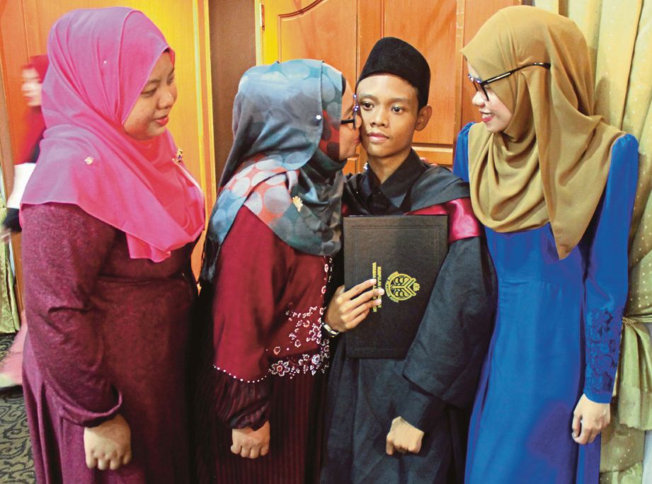 AHMAD Nor Bakti  dikucup ibunya, Zaiton  sambil diperhatikan dua kakaknya, Husna, 25, (kanan) dan Izatie, 26, pada Majlis Konvokesyen ke-19 Kumpulan Pendidikan YPJ yang diadakan di Dewan Sultan Iskandar, UTM, Johor Bahru.