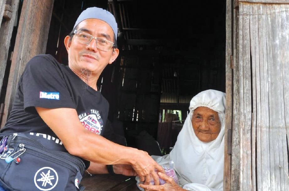 KASSIM Lim Abdullah (kiri) mengagihkan daging korban kepada penduduk kampung.