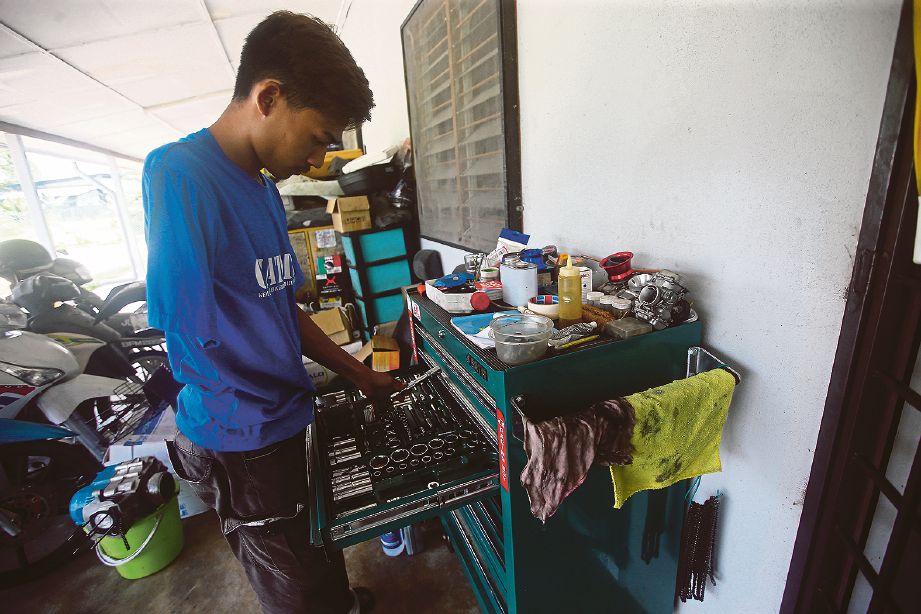 MOHAMMAD Arif mengambil peralatan untuk membaiki kenderaan.