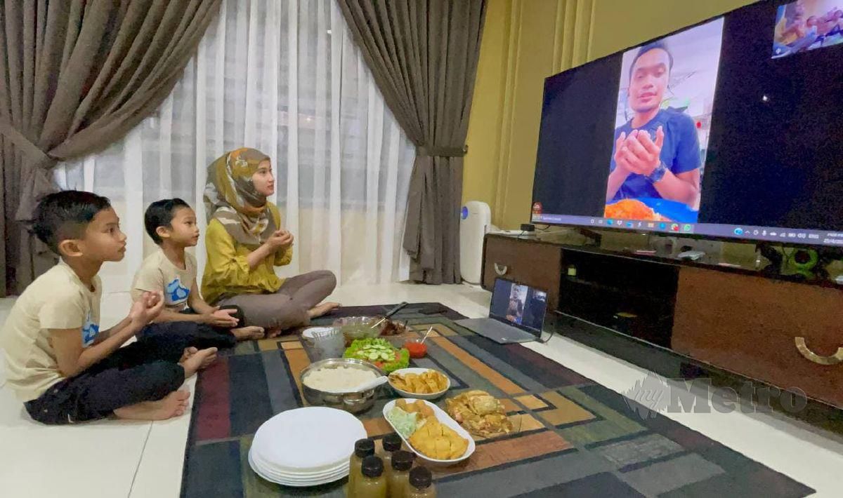 Isteri, Nor Fazilah Deris, 33,  ditemani anaknya  Muhammad Danish Anaqi , 8, dan Muhammad Dinie Asyraf, 6, membuat panggilan video bersama suaminya Muhammad Razi Abdul Ghani, 34, yang berada di Singapura ketika waktu berbuka puasa bersama-sama di rumah mereka di Taman Scientex, Senai, Johor. FOTO NUR AISYAH MAZALAN