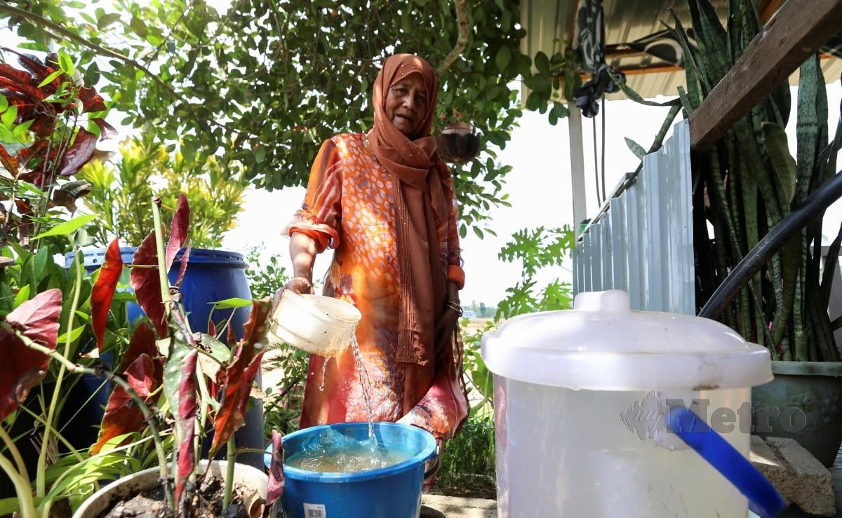 Peniaga kedai makan, Zainab Miros, 75, menunjukkan air yang keruh selepas  menggunakan telaga tiub ketika ditemui di Kampung Dewan Beta di sini. FOTO NIK ABDULLAH NIK OMAR