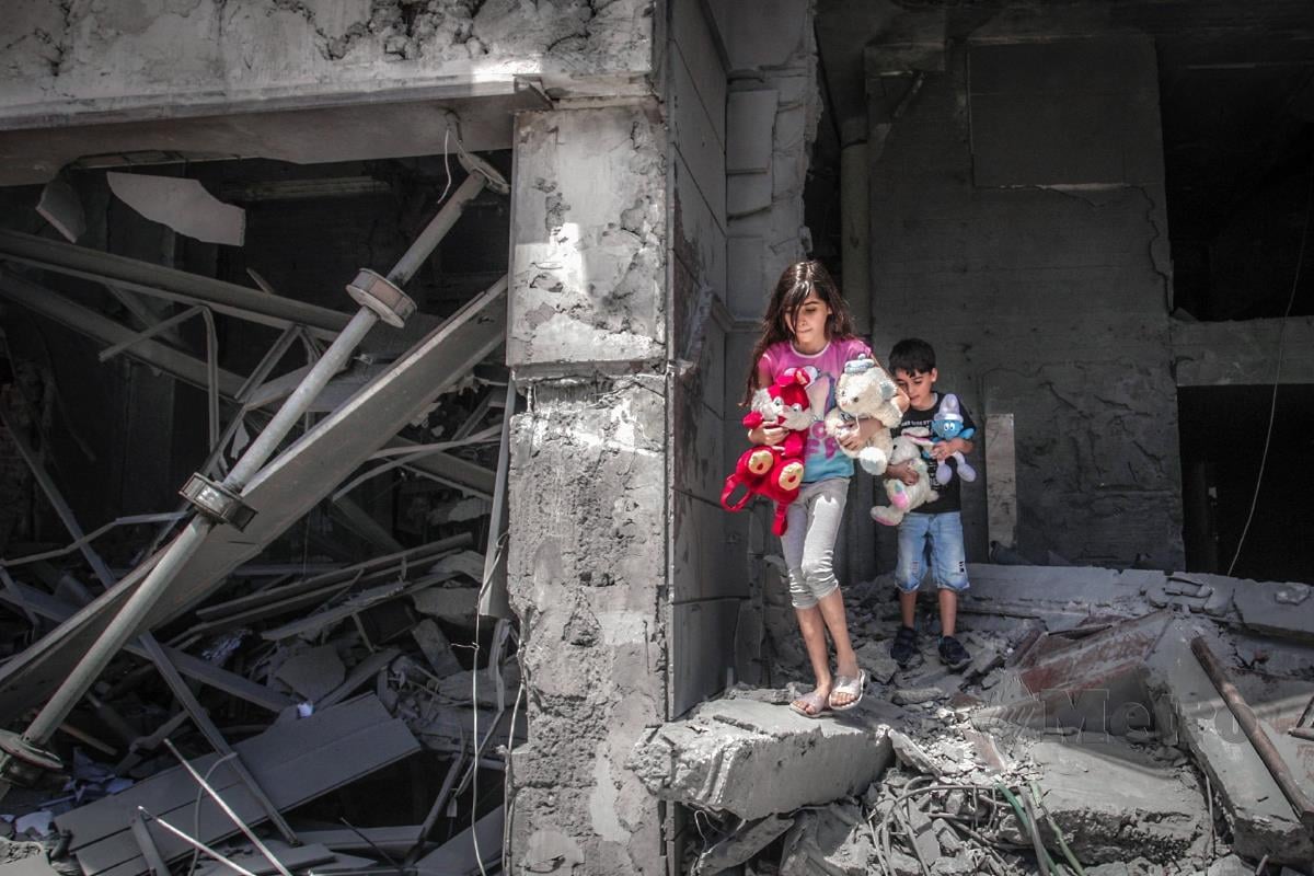Kanak-kanak di Palestin menyelamatkan permainan mereka selepas kediaman mereka musnah akibat serangan udara Israel. FOTO AFP