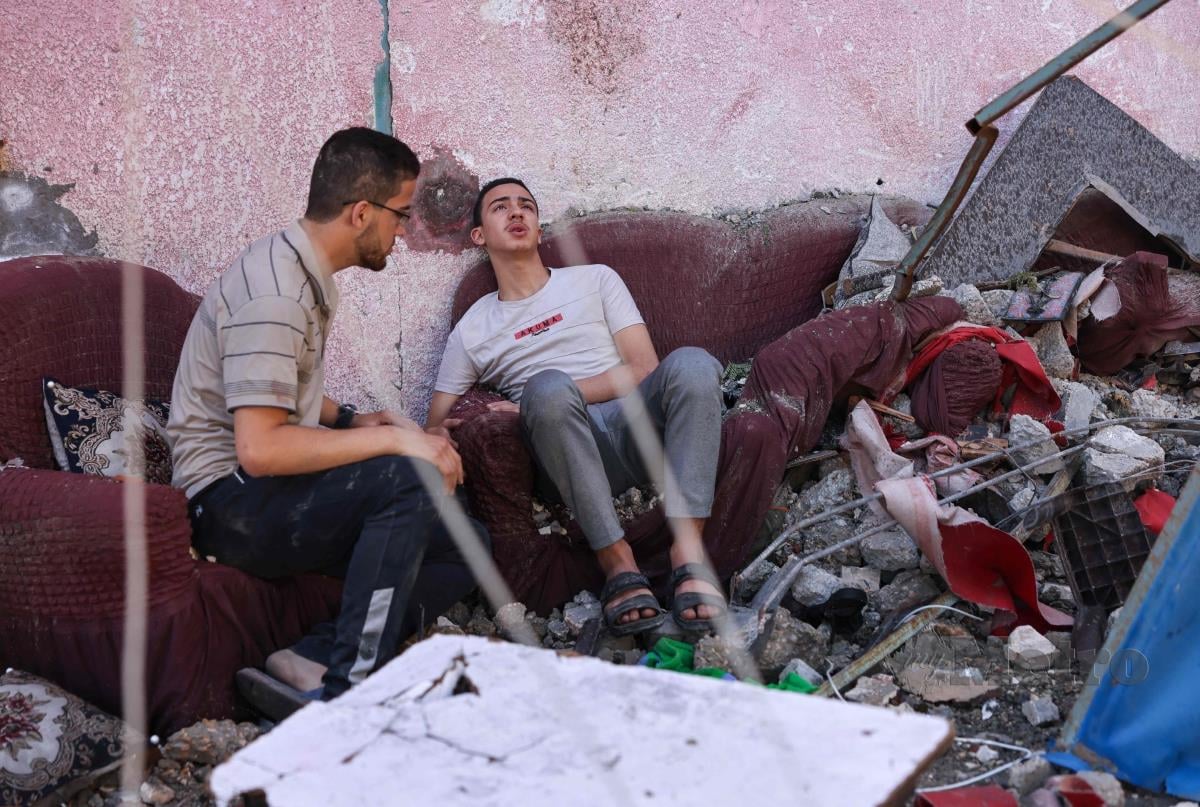 Rakyat Palestin duduk melihat kediamannya musnah selepas diserang tentera Israel. FOTO AFP