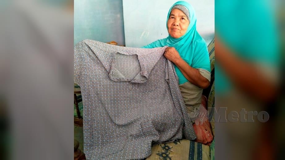 CHE Minah Yaacob, 64, menunjukkan baju Melayu milik anaknya, Adnan Che Soh, 29, yang masih belum dijumpai setelah hanyut di Sungai Nenggiri dua tahun lalu semasa ditemui di Kampung Prak. FOTO Ramli Ibrahim