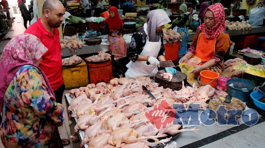 PENIAGA ayam, Zarina Abdullah, 49, (kanan) melayan pelanggan yang membeli ayamnya di Pasar Besar Siti Khadijah. FOTO Nik Abdullah Nik Omar