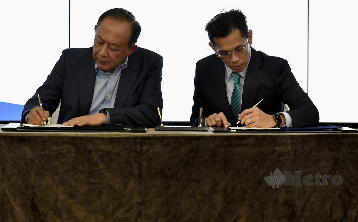 MAHMUD (kiri) dan Jay Khairil menandatangani dokumen di Ibu Pejabat PKNS, Shah Alam.