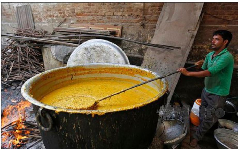 GAMBAR menunjukkan pekerja memasak gulai di dalam periuk. - Reuters