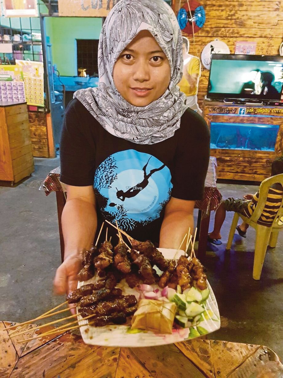 PETUGAS gerai Pak Jakpau Corner menunjukkan hidangan sate tulang bersama ketupat.