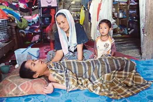 Idurai (tengah) bersama anak bongsunya menjaga Mohd Aqiudin yang menghidap penyakit sawan sejak berumur 8 bulan di rumahnya.