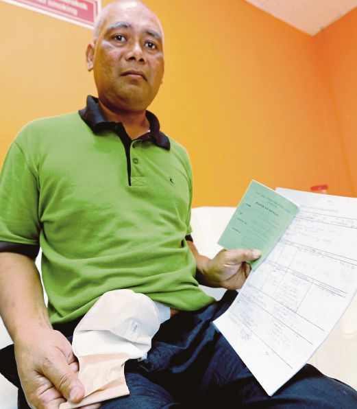Abdul Aziz   menunjukkan beg stoma untuk membuang najis dan surat rawatan penyakitnya.