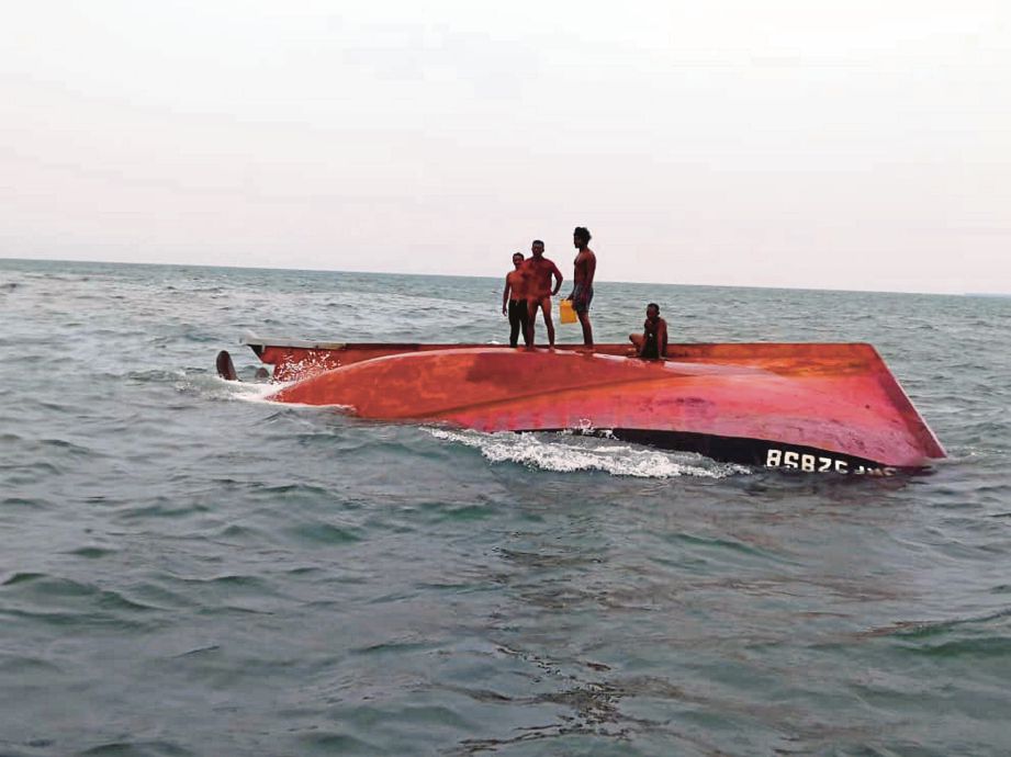 EMPAT awak-awak menyelamatkan diri di atas bot yang terbalik sebelum diselamatkan pasukan Maritim Malaysia kira-kira 9.5 batu nautika Barat Daya Tanjung Tohor Batu Pahat. FOTO ihsan Maritim Malaysia
