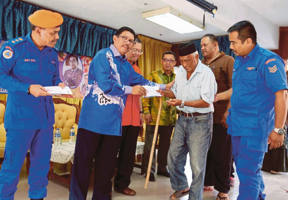 Mohd Halim (dua dari kiri) menyampaikan sumbangan kepada  Mohamad Saifol Sadiman  di Kampung Kangkar Tebrau, Johor Bahru. 