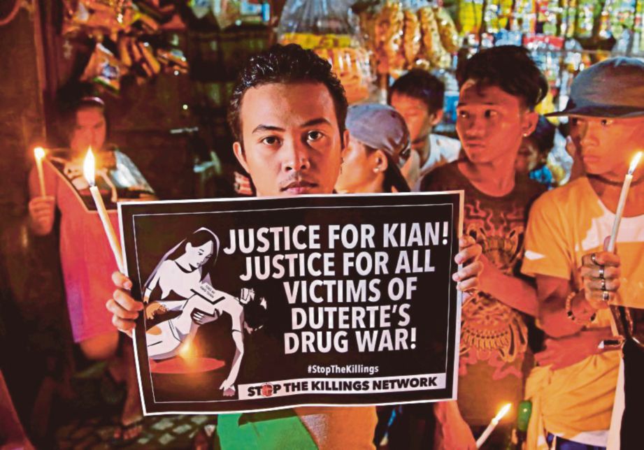SEORANG lelaki memegang poster ketika menyertai bantahan terhadap kempen antidadah polis di Manila. - Agensi