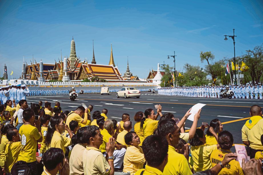 ORANG ramai menunjukkan potret dan wang kertas yang mempunyai wajah Raja Maha Vajiralongkorn ketika konvoi kenderaan diraja tiba di Istana Besar. FOTO AFP