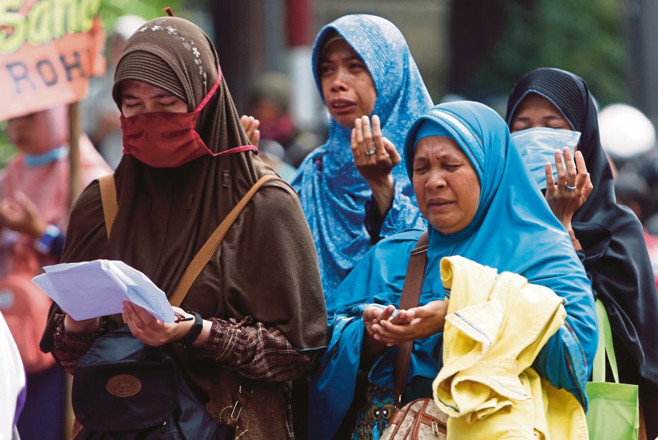 AKTIVIS menangis semasa bacaan doa ketika bantahan kekejaman terhadap Rohingya di hadapan kedutaan Myanmar di Jakarta, semalam. - EPA