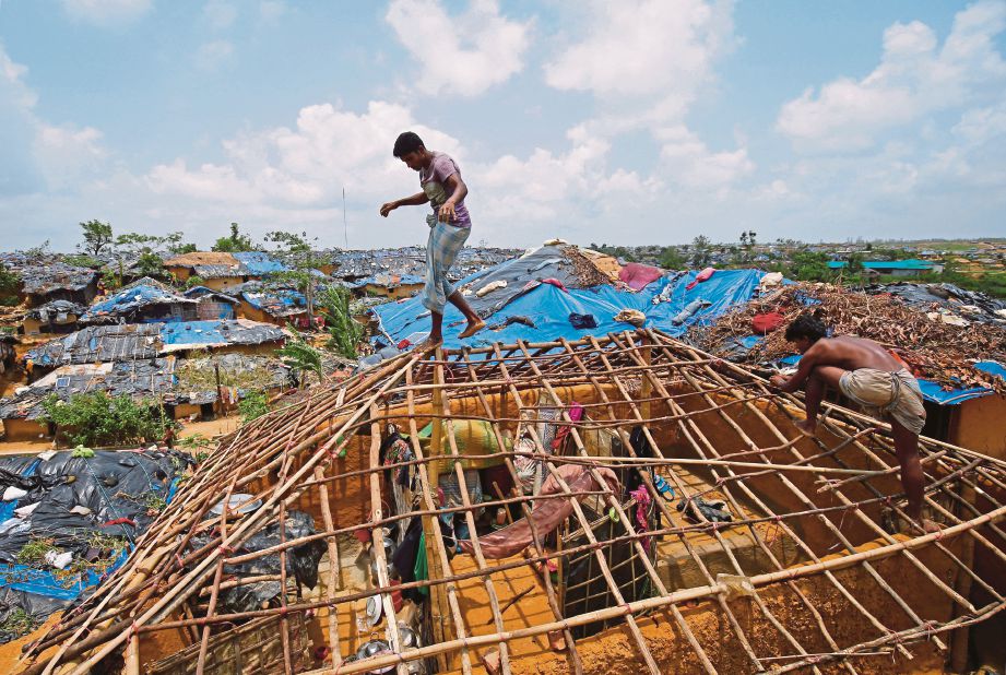 PELARIAN Rohingya membina semula kediaman mereka yang dimusnahkan taufan Mora.