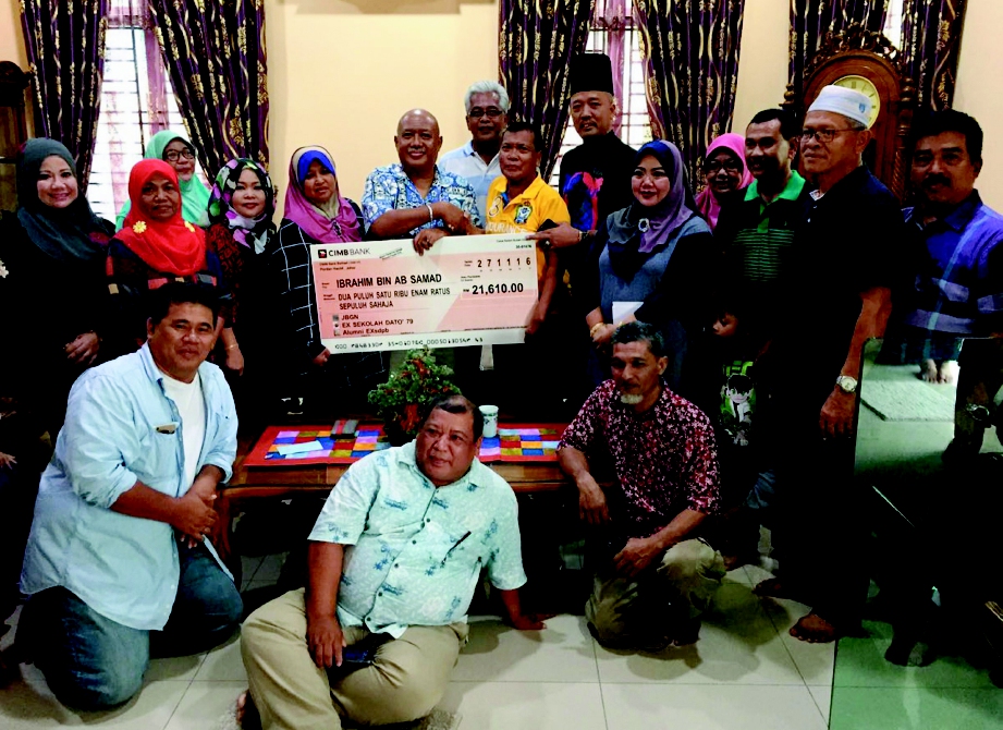 IBRAHIM (baju kuning) menerima replika cek sumbangan  bekas pelajar Sekolah Dato’ Penggawa Barat, Pontian di kediamannya.