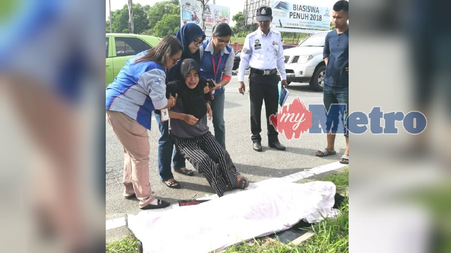 SURAYA Darus, 44, terpaksa dipapah selepas melihat mayat madunya Siti Aishah Mohamad Yusof terbaring selepas terbabit kemalangan berhampiran SMK Teknik pagi tadi. FOTO Omar Osman