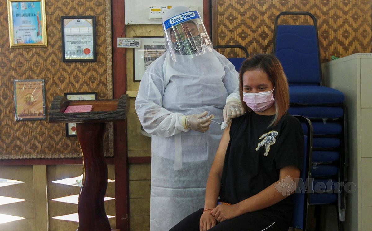 Seorang petugas kesihatan membuat suntikan vaksin kepada seorang penerima di Kampung Orang Asli Bukit Kepong. FOTO AZRUL EDHAM MOHD AMINUDDIN