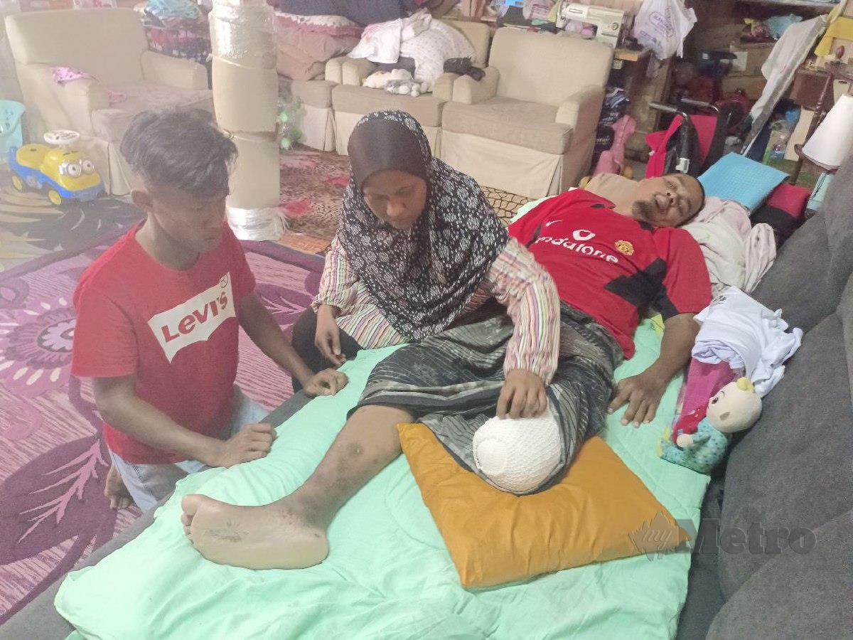 Norhayati Harun, 43, menguruskan suaminya, Mohd Husaini Husin, 42, yang kakinya dipotong akibat kencing manis di Kampung Gong Gemia, di sini. FOTO FAIZUL AZLAN RAZAK