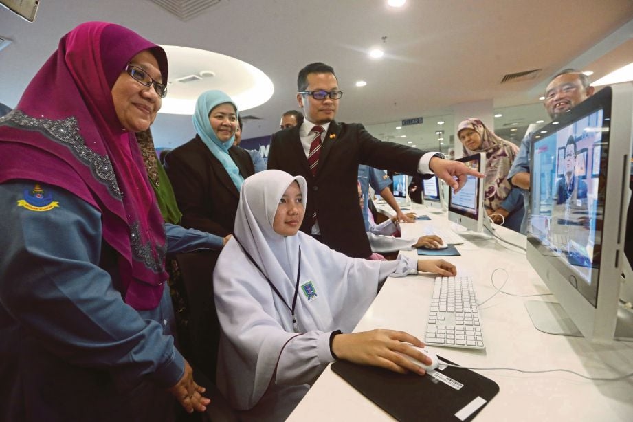  ZAHURA  (kiri) melihat pelajar tingkatan lima  mendaftar Program Tuisyen Atas Talian  di Perpustakaan Raja Tun Uda. 