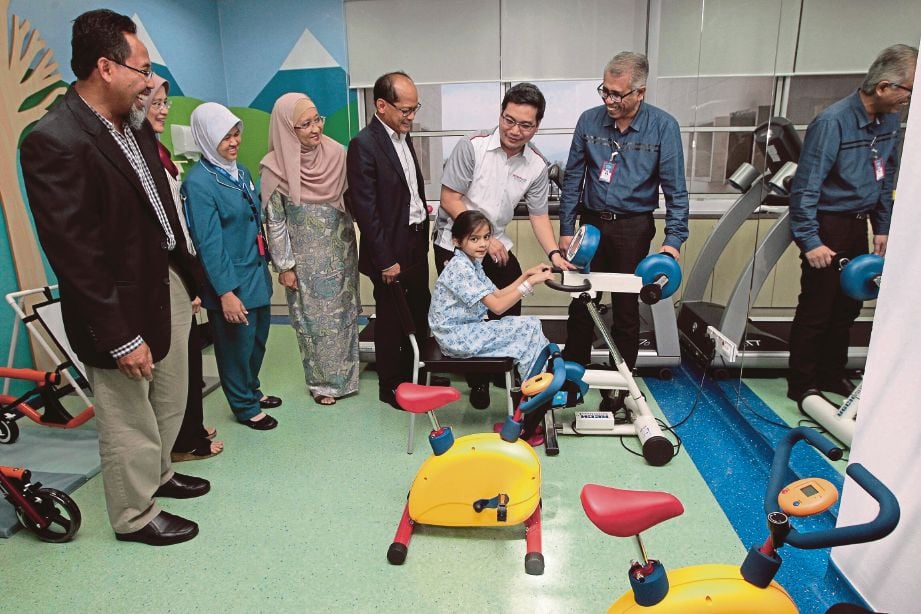 ZURAIDA (empat dari kiri), Dr Mohd Azhari (lima dari kiri) dan Wan Saifulrizal (dua dari kanan) melihat pesakit, Nur Hani Natasha, 10, menggunakan kemudahan fisioterapi pada majlis pelancaran kemudahan fisioterapi Pediatrik IJN untuk kanak-kanak di IJN, semalam.