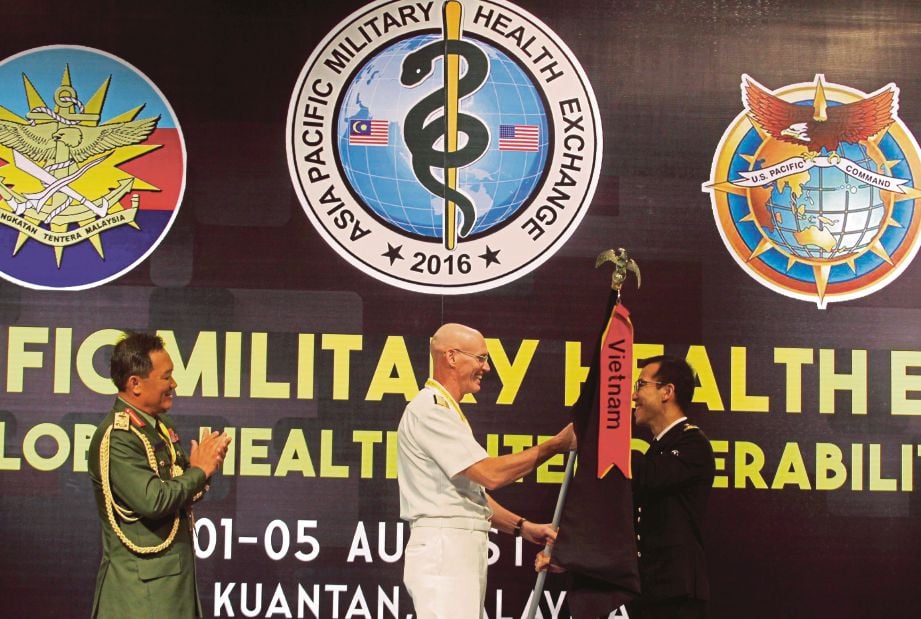 DR Abdul Razak menyaksikan Pakar Bedah Pasifik Amerika Syarikat Laksamana Madya Brian Pecha (tengah) menyerahkan bendera kepada tuan rumah APMHE 2017 kepada Ketua Perubatan Angkatan Tentera Singapura, Laksamana Muda Tang Kong Choong, semalam. 