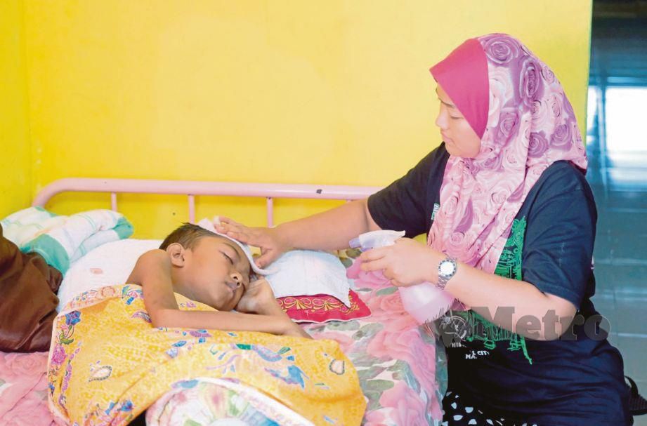 NOR Sakilawati mengelap tuala basah di kepala anaknya, Muhammad Saiful 11, yang menghidap barah neuroblastoma. FOTO Noorazura Abdul Rahman