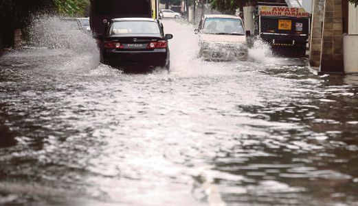 PENGGUNA meredah banjir kilat di Lorong Mak Mandin 5 dan Tingkat Mak Mandin 3, semalam.