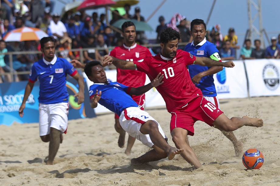 PEMAIN Iran, Moslem  (kanan) diasak pemain negara,   Rozairi Ahmad di Pantai Batu Buruk, semalam.