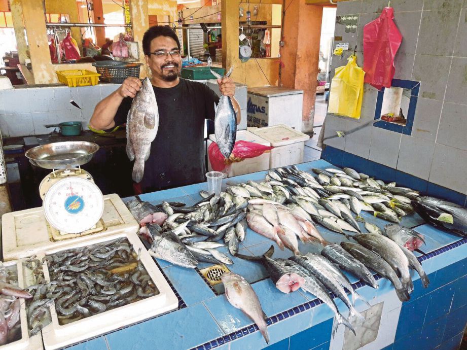 MOHD Saifudin menunjukkan ikan kerapu bulat berharga RM30 sekilogram (kiri) dan ikan tongkol berharga RM14 sekilogram di Pasar Bukit Besar.