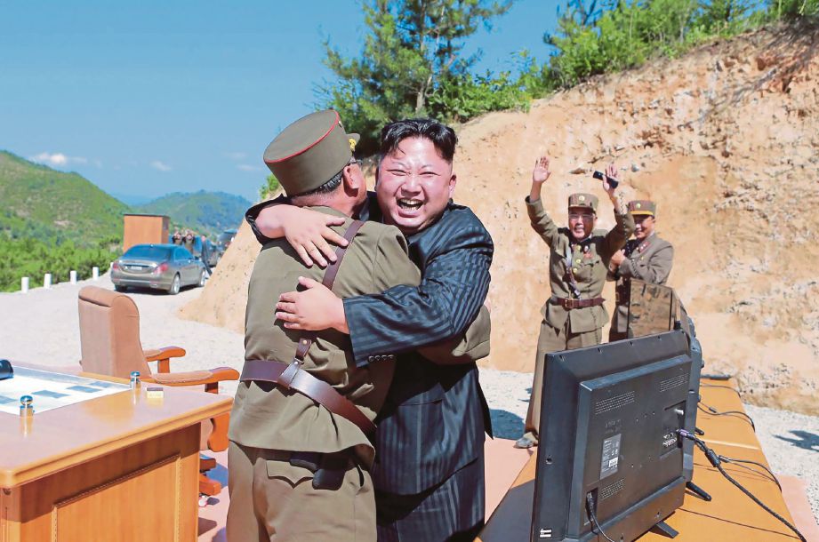GAMBAR yang dirakam pada 4 Julai lalu menunjukkan Kim Jong Un memeluk pegawainya sebaik kejayaan menguji peluru berpandu terbaru negaranya.  Gambar kecil, peluru berpandu Hwasong 14 yang didakwa mampu dilengkapi peledak nuklear.  - AFP 