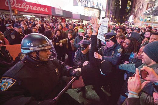 Anggota polis menahan seorang penunjuk perasaan di Times Square.