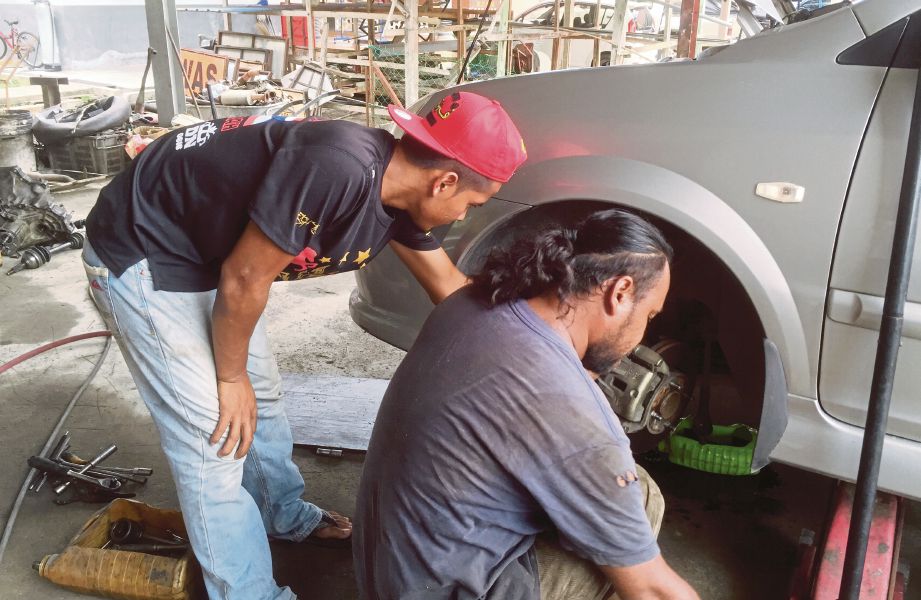 MULUK (kanan) mengajar golongan muda membaiki kereta.