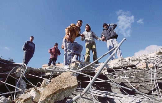 PENDUDUK Palestin berdiri di atas runtuhan bangunan yang dimusnahkan oleh tentera Israel di Hebron, Tebing Barat, semalam.  