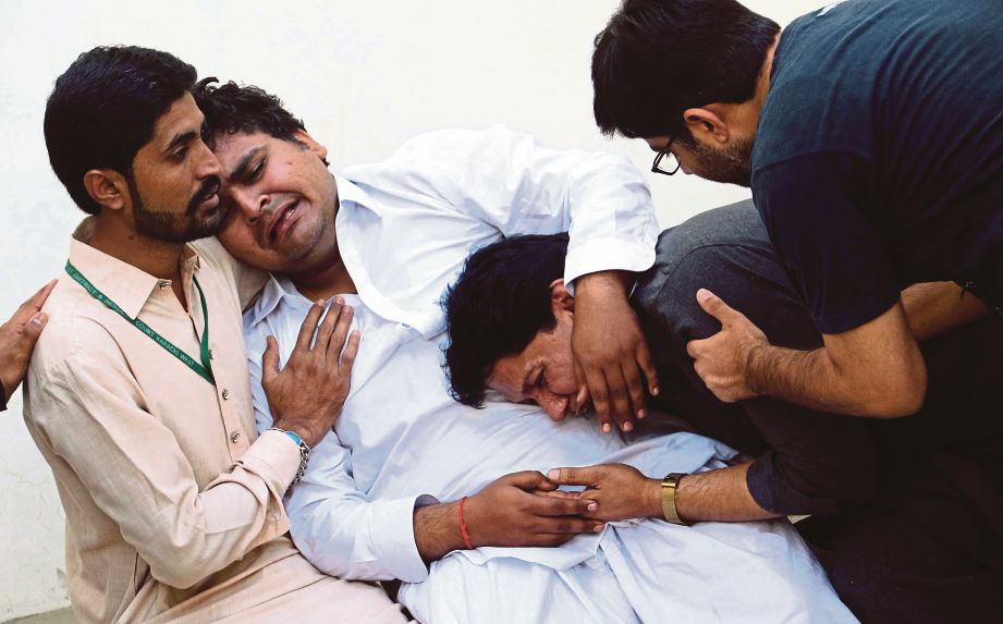 KELUARGA mangsa yang maut dalam kebakaran menangis di sebuah hospital di Karachi. - EPA 