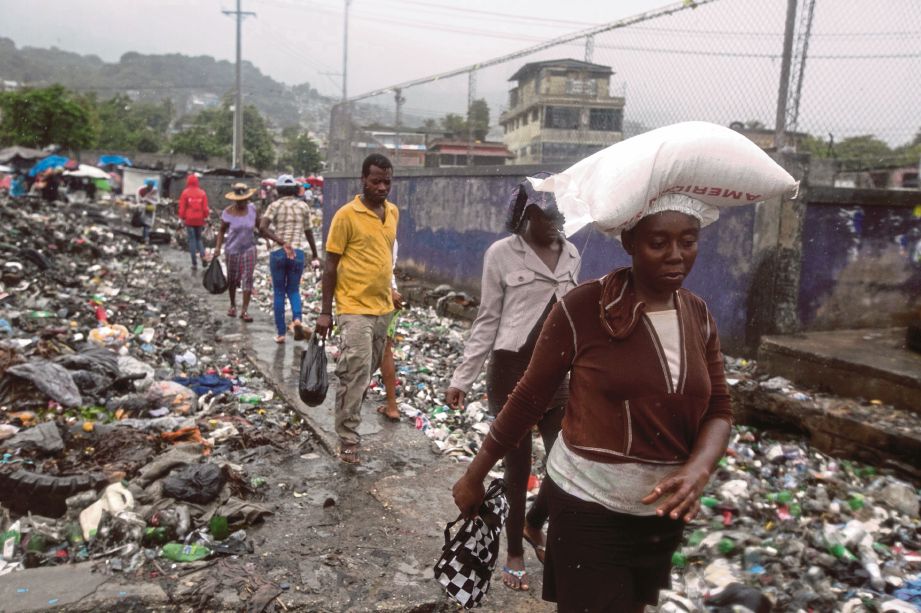 PENDUDUK berjalan melintasi sampah sarap di Port-au-Prince, Haiti.  