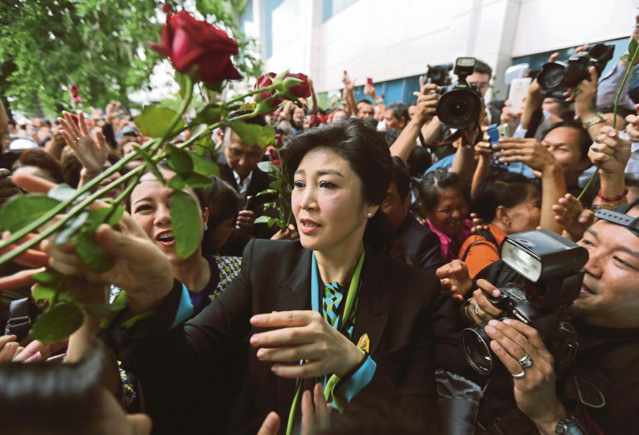 YINGLUCK terima bunga daripada penyokongnya ketika tiba di bangunan mahkamah di Bangkok, semalam. - EPA