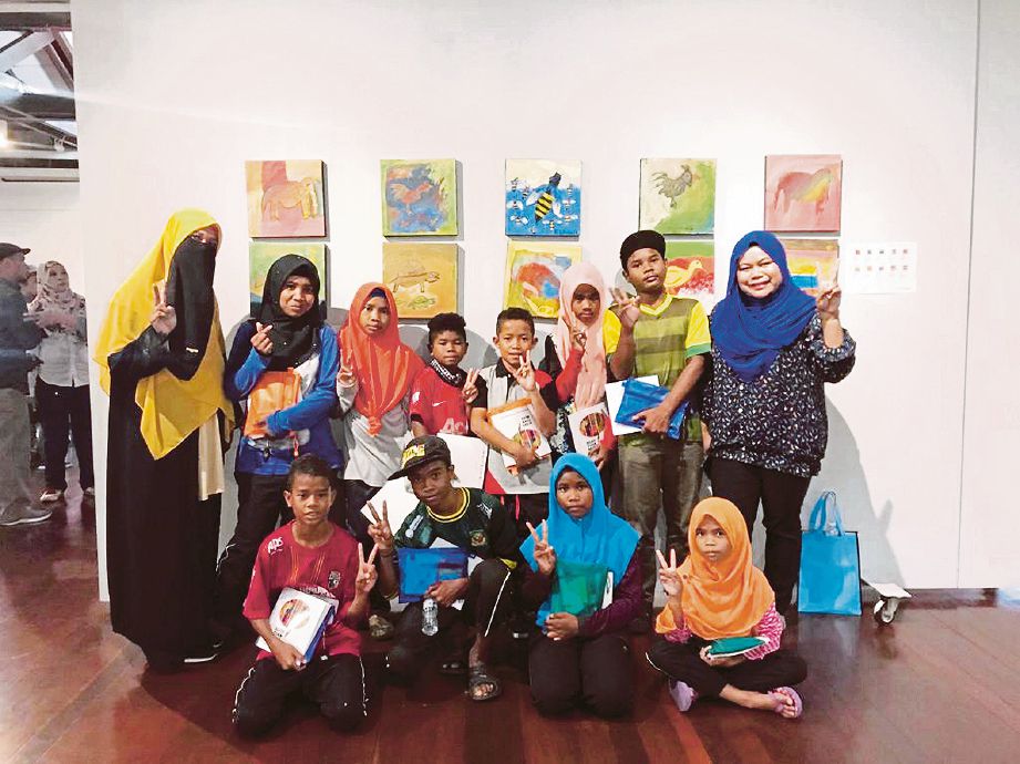 PESERTA pameran kanak-kanak Orang Asli dari Perpustakaan Permainan, Kampung Desa Damai, Belum-Temengor, Gerik bersama karya mereka.
