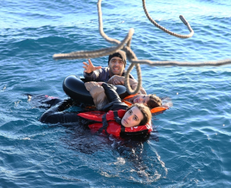 PENDATANG ini cuba mencapai tali untuk diselamatkan selepas bot yang dinaiki mereka karam di Laut Mediterranean.  