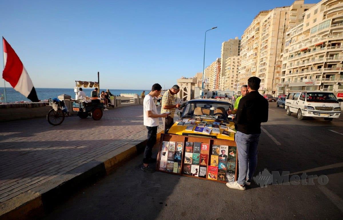 Orang ramai membaca buku yang diletakkan di atas teksi. FOTO Reuters