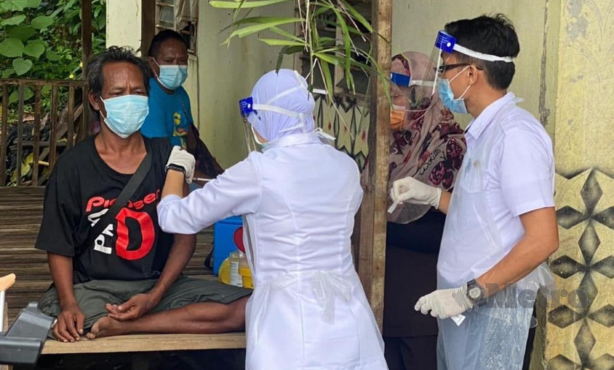 Penduduk yang juga orang kelainan upaya (OKU) menerima suntikan vaksin di rumahnya di Kampung Orang Asli Bukit Payung. FOTO NURALIAWATI SABRI
