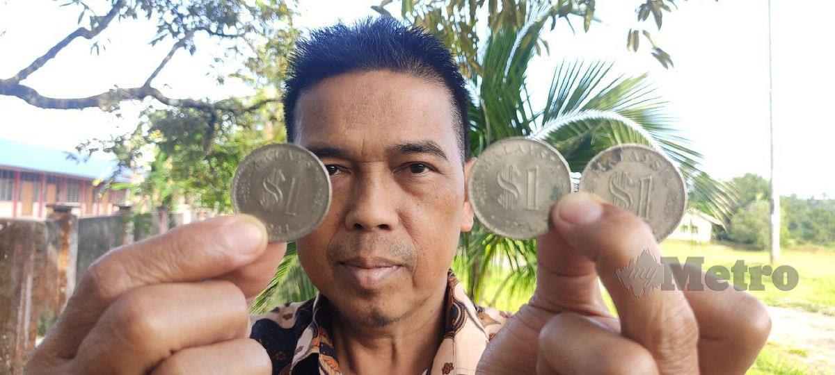 Ahmad Zaharudin Amin menunjukkan duit syiling RM 1.00 berusia 51 tahun dan 38 tahun. FOTO ROSMAN SHAMSUDIN