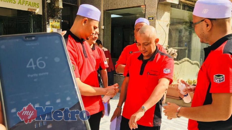 PETUGAS TH di Madinah meyembur air daripada botol kecil ke bahagian tubuh yang kering akibat cuaca panas mencecah 46 darjah celsius. FOTO Tuan Asri Tuan Hussein