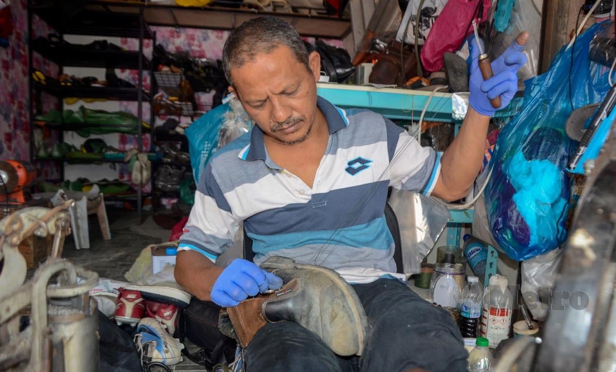 Tukang kasut, Kamaruzaman Mat Zin, 50, menjahit kasut pelanggannya di kedai yang terletak di Bandar Tanah Merah, di sini. FOTO BERNAMA