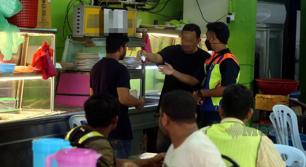 Angota penguatkuasa DBKL memeriksa pengenalan lelaki yang disyaki memberi rasuah kepada penguatkuasa ketika operasi Khas SPRM Bersama DBKL 'Ops Star' di Japan Padang, Bukit Bintang. FOTO HAIRUL ANUAR RAHIM